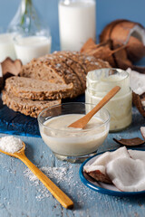 Organic healthy coconut butter and fresh coconut pieces on blue wooden background.