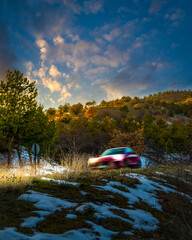 Obraz na płótnie Canvas Car driving through hills on a snowy and sunny day with motion blur, evening. Lake Eymir, Ankara, Turkey.