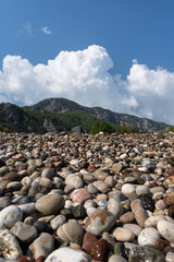 Wet and shiny pebbles from a beach in south Turkey with white clouds in the background, very shallow focus

