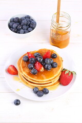 Still life with pancakes, berries and honey on a white background