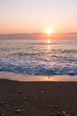 A beach in south Turkey at sunrise time with sand and pebbles in the foreground, motion blur of the waves