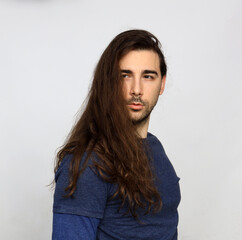 Attractive male model with long hair and beard is posing in studio. Style, trends, fashion concept.