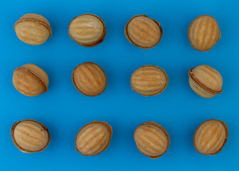A group of nut-shaped cookies stuffed with boiled condensed milk on a blue background.