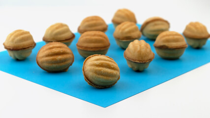 A group of nut-shaped cookies stuffed with boiled condensed milk on a blue background.
