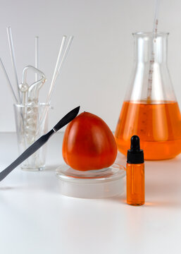 Ripe organic persimmon fruit and persimmon extract in cosmetic bottle with dropper. Abstract chemical or cosmetic laboratory.