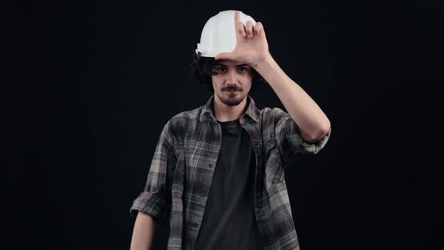 Hipster pointing to the lost gesture and pointing to the room, with a sarcastic, mocking smile on his face. Young man with curly hair wears a special helmet on his head, dressed in a plaid shirt, on a