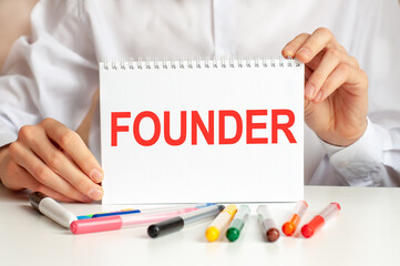 A sheet of paper with text jfounder, multicolored markers on a white table. Business and...
