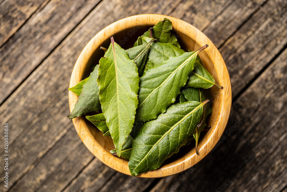 Wall mural fresh green bay leaves in wooden bowl.