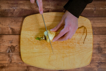 Someone cutting into a fresh parsnip with a knife.