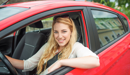 Fototapeta na wymiar Happy beautiful woman is driving a red car.