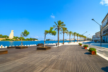 Palm trees line the waterfront boardwalk and promenade at the port harbor of Brindisi, Italy, in the Southern Puglia region