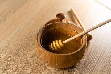 honey in a deep wooden bowl, rustic wooden plate. The wooden spoon drips slowly.