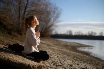 Practice of meditation and interaction with nature. Girl near river