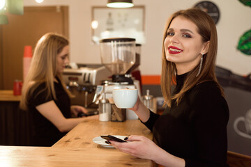 Smiling woman in a good mood enjoy cup of coffee sitting in a cafe.
