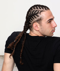 Attractive guy with braids posing in studio on isolated background. Style, trends, fashion concept.