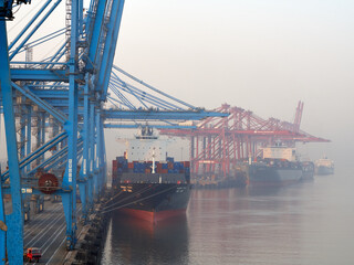 India, Mumbai Port Trust - 25 January, 2017: View to moored container vessels with port cranes during the morning fog.