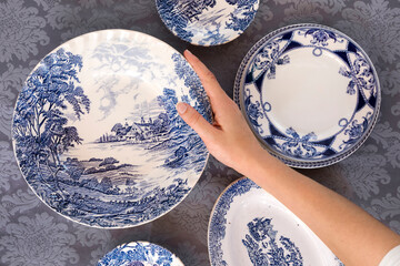 Hand holding a blue plate on floral textile table, passover 15th day of Nisan, Jewish holiday, with circle shape