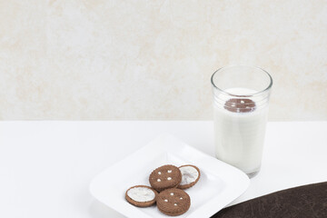 galleta con un vaso de leche sobre una mesa blanca