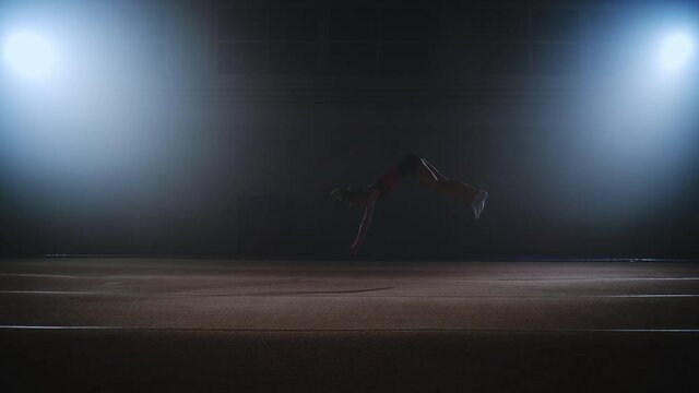stunning slow motion shot of young female gymnast performing somersault on spring floor