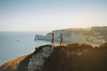 a guy with a girl stand holding hand on a cliff on the sea coast side view