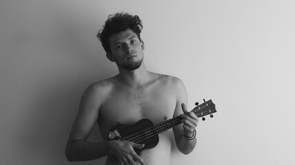 
Parne' s ukulele na fone beloy steny
Guy with ukulele on white wall background