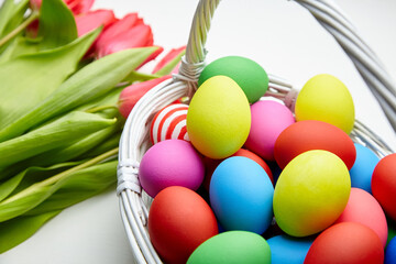 Easter Eggs in basket and spring flowers on white wooden table
