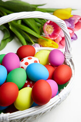 Easter eggs in basket and spring colorful flowers on white wooden table