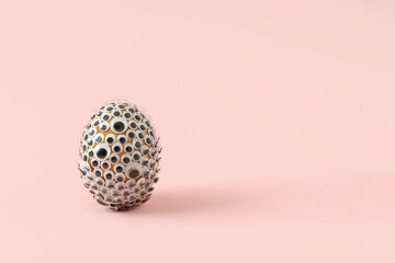 Natural Easter egg covered with googly eyes on pink background. Funny holiday concept.