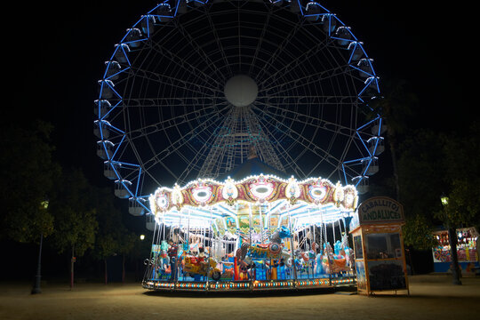 Illuminated carousel and ferris wheel at night, Seville, Andalusia, Spain