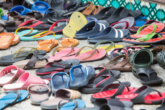 Rows of footwear and flip flops on sidewalk outside Mosque, 
Malacca, Malaysia