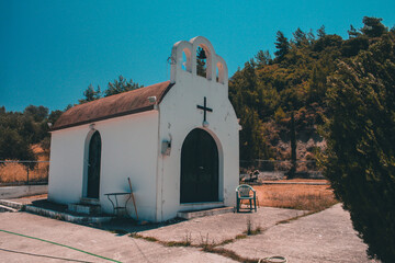 Typical greek church in white color and red roof and cemetery in the fron in warm hot day.