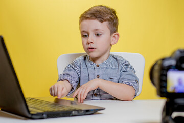 Kid blogger filming video on camera working with the laptop.