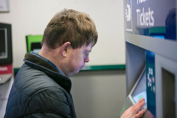 Man with down syndrome at train ticket machine, Galway, Ireland