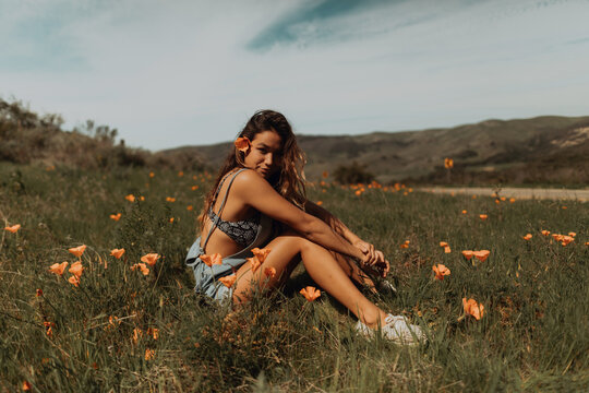 Young woman sitting in field of wildflowers, portrait, Jalama, California, USA