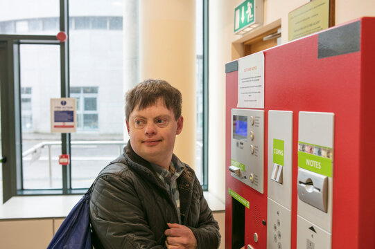 Man with down syndrome at ticket machine in train station, Galway, Ireland