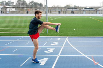 Fototapeta premium Happy boy wearing sports clothes doing warm-up before workout in the stadium.