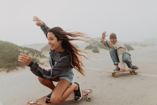 Young couple skateboarding in misty beach carpark, Jalama, California, USA