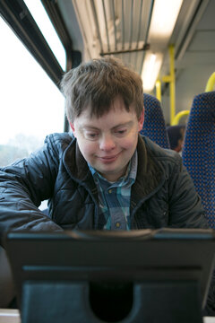 Man with down syndrome watching film on digital tablet on train