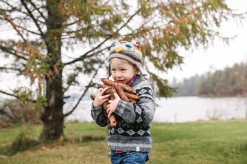 Boy with armful of brown pine cones, Kingston, Ontario, Canada