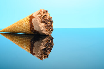 fresh chocolate flavor ice cream cone on glass with reflection on blue background