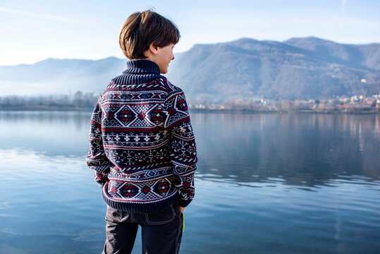 Boy looking out from lakeside, rear view, Lake Como, Lecco, Lombardy, Italy