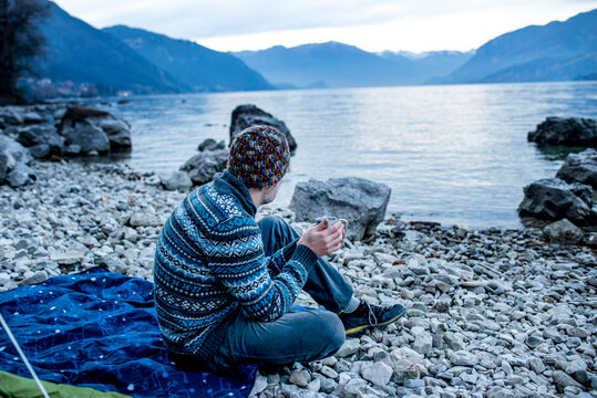 Man camping on lakeside, Onno, Lombardy, Italy