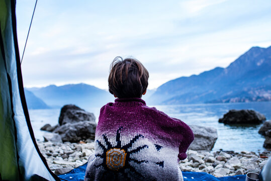 Boy looking out over lake from tent, rear view, Lake Como, Onno, Lombardy, Italy