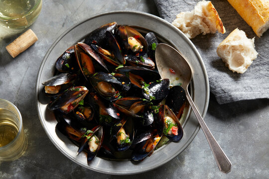 Bowl of garlic mussels with glass of white wine, overhead view