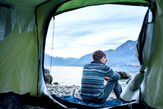 Man camping on lakeside, view from inside tent, Onno, Lombardy, Italy