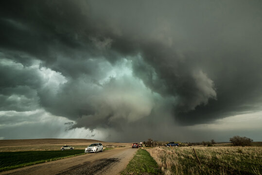 Fototapeta Monster supercell with developing wall cloud moves across central Kansas and later forms a destructive, EF-3 rated tornado destroyed property. Storm chasers observing  storm on dirt road, USA