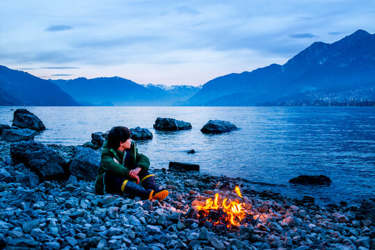 Boy by campfire at dusk, Onno, Lombardy, Italy