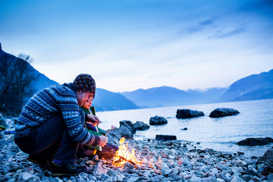 Father and son toasting marshmallows over campfire, Onno, Lombardy, Italy