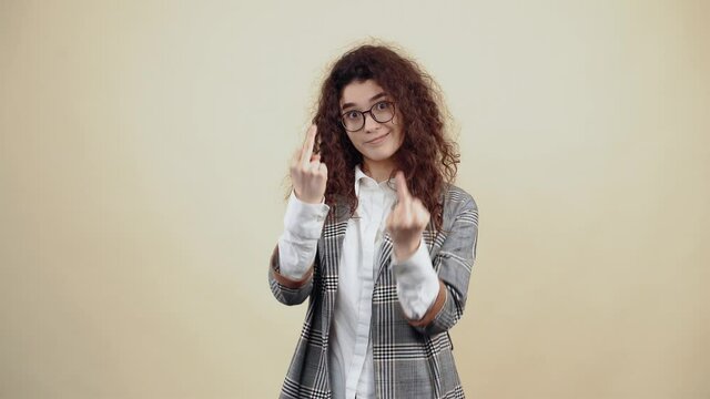 The revolted young woman points her middle finger with both hands and looks into the room, insistently waving her hand. Cretaceous in gray jacket and white shirt, with glasses posing isolated on a