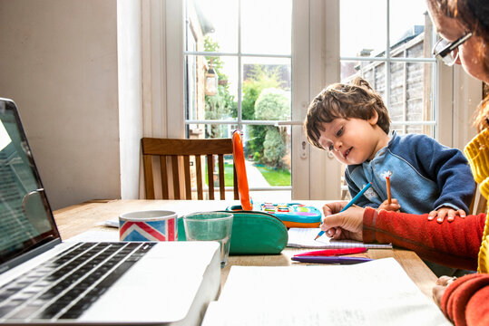 Toddler boy learning from mother working from home
